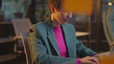 Pembe saçlı gülümseyen kadın LGBT çıkartmalı dizüstü bilgisayar kullanıyor. Ofis gecesinde mutlu oluyor.