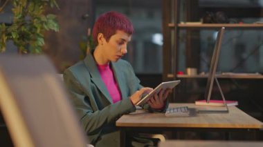 Pembe saçlı ciddi bir kadın ofis gecesinde bilgisayarında LGBT çıkartması kullanır.