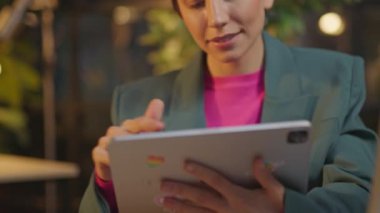 Pembe saçlı kadın, gece ofiste LGBT çıkartmalı tablet bilgisayar kullanıyor.