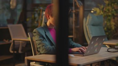 Modern ofis kadınlarında pembe saçlı kadınlar akşamları LGBT çıkartmalı dizüstü bilgisayar kullanırlar.