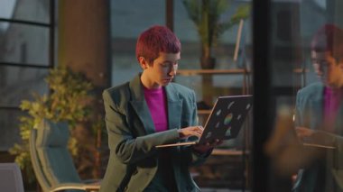 Modern ofis kadınlarında pembe saçlı kadınlar akşamları LGBT çıkartmalı dizüstü bilgisayar kullanırlar.