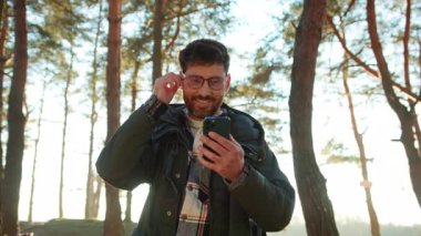 Spor giyim sektöründe gülümseyen erkek turistin akıllı telefon navigatörünü kullanırken görüntüsü.