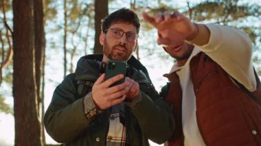 Afrika kökenli Amerikalı genç adam konuşuyor ve erkek arkadaşına ormanda yol gösteriyor.