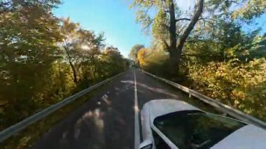 Otoyolda hızla ilerleyen beyaz modern arabanın geniş açılı görüntüsü. Kırsal manzaralı kırsal çevre. Yolculuk. Yolculuk.