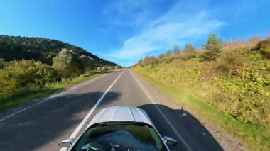 Geniş açılı beyaz araba kırsal alanda otoban boyunca hızla ilerliyor. Güneşli bir gün. Yolculuk. Aktarım.