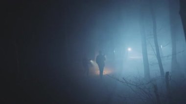 Dedektifler geceleri ormanda fenerli genç adamlar. Orman, güvenlik, ekipman, projektör, sis, suçlu. FPV Drone