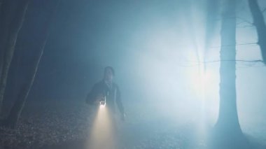 Ciddi dedektifler geceleri ormanda fenerli genç adamlar. Orman, güvenlik, ekipman, projektör, sis, suçlu. FPV Drone