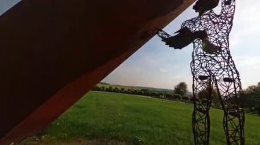 Hız hareketi. Harika bir parkın FPV manzarası. Açık alanda heykellerin sergilenmesi. Güzel manzara tasarımı. Yeşil alanın ortasında beyaz modern heykelin havadan çekilmiş yatay çekimi. Açık havada. Gökyüzü.