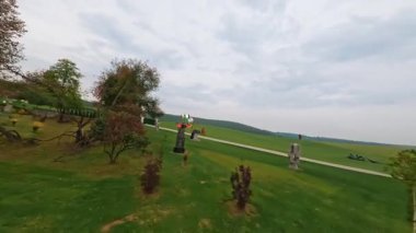 Hızlı İHA FPV 'nin modern heykel ve sanat alanı ile sinematik park üzerinde uçuşu görüntüleri. İlhamın yeri. Fiuture sineması parkı. Yeşil alanın yatay görüntüsü. Yaz vakti, şehir dışında..