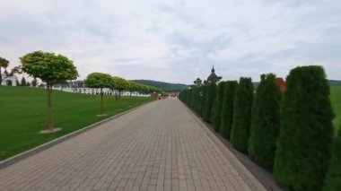 Hızlı İHA FPV 'nin güzel peyzaj tasarımı ve patikalarla park üzerinde uçuşu görüntüleri. Yaz mavisi gökyüzü bulutları. Yeşil ağaçlar ve patikalarla halka açık bir park. Hız hareketi. Açık hava..