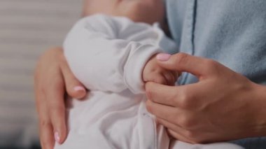 Yeni doğmuş bir bebeği kucağında tutan güzel bir genç kadın rahat bir evde duruyor. Bebek annesinin kollarında uyuyor. Annelik. Çocukluk. Anne elini tutuyor, çocuk. Yavaş çekim