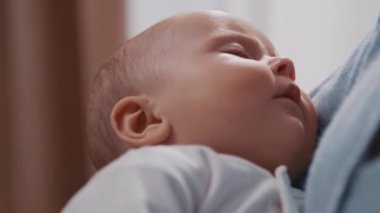 Yeni doğmuş şirin bir bebeğin annesinin kollarında rahat bir evde uyuması. Annelik. Çocukluk. Anne elini tutuyor, çocuk. Yavaş çekim