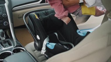 Eller, anne, yeni doğmuş bebeğini bebek koltuğuna oturtuyor ve bir çocukla arabaya binerken emniyet kemeri takıyor. Öpüşme. Komik çocuk. Çocukluk. Mutluyum. Yavaş çekim