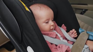 Bebek koltuğunda oturan sevimli küçük kız mutlu bir duygu ifadesi hissediyor. Çocuk arabanın içindedir. Araç ve ulaşım konsepti. Seyahat et. Yavaş çekim.