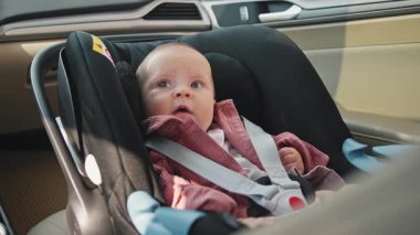 Bebek koltuğunda oturan sevimli küçük kız mutlu bir duygu ifadesi hissediyor. Çocuk arabanın içindedir. Araç ve ulaşım konsepti. Seyahat et. Yavaş çekim