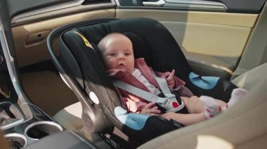 Bebek koltuğunda oturan sevimli küçük kızın portresi mutlu bir duygu ifadesi veriyor. Çocuk arabanın içindedir. Araç ve ulaşım konsepti. Seyahat et. Yavaş çekim