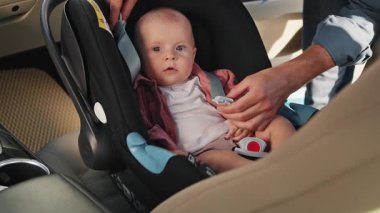 Babası, yeni doğmuş bebeğini bebek koltuğuna oturtuyor ve bir çocukla arabaya binerken emniyet kemeri takıyor. Öpüşme. Komik çocuk. Çocukluk. Mutluyum. Yavaş çekim