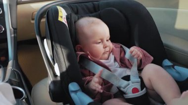 Bebek koltuğunda oturan sevimli, sevimli küçük bir kız annesiyle oynadığı için mutlu. Çocuk arabanın içindedir. Araç ve ulaşım konsepti. Seyahat et. Yavaş çekim