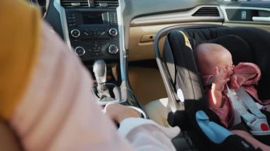 Bebek oto koltuğunda oturan sevimli küçük kız portresi annesinin eliyle oynamaktan mutluluk duyuyor. Çocuk arabanın içindedir. Araç ve ulaşım konsepti. Seyahat et. Yavaş çekim