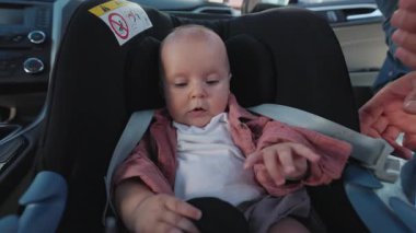 Sevimli bebek ve baba portresi, arabada bir çocukla yapılan ortak bir gezi sırasında emniyet kemerlerini araba koltuğuna bağlıyor. Öpüşme. Komik çocuk. Çocukluk. Mutluyum. Yavaş çekim
