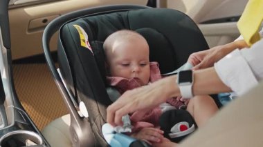 Çocuk emniyet koltuğunda oturuyor. Annenin elleri sürüşten önce emniyet kemerini çocuğa bağlıyor. Yolculuk sırasında koruma. Sabah oldu. Seyahat, hafta sonu