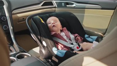 Bebek koltuğunda oturan küçük tatlı bir çocuğu vurmak. Arabanın içindeki çocuğun portresi. Araç ve ulaşım konsepti. Güzel bebek güvende. Seyahat
