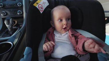 Çocuk oto koltuğunda oturan mutlu çocuğun yakın çekim görüntüleri var. Bebek otomatik olarak güvenli bir şekilde taşınıyor. Duygu, ifade. Rahat ulaşım. Güvenlik ve güvenlik