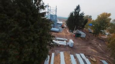 Sanayi fabrikasının dışında. Modern teknoloji. Otomasyon fabrikada. Ekipman görüntüsü. Sonbahar, yeşil ve sarı ağaçlar. Hızlı İHA FPV uçağı. Beyaz kasklı beyaz müteahhitler el sıkışıyor. Açık havada. Taş ocağı.