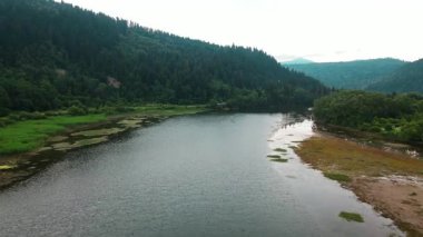 Hava aracı bulutlu bir günde sakin nehir gölü manzaralı su dalgaları üzerinde uçuyor. Macera manzaralı. Doğal ortam. Ekoloji.