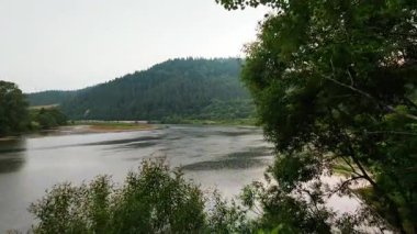 Bulutlu bir havada yaz ortamına göz kamaştırıcı bir manzara. Sinema sakin göl, orman tepeleri ve sakin doğa..