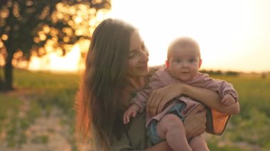 Annenin gün batımında kızıyla birlikte ayçiçeği tarlasında dikilirken yakın çekim. Çocukluk konsepti. Rahatlamak ve dışarıda iyi vakit geçirmek..