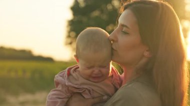 Anne, kızını ayçiçeği tarlasında kollarına aldı. Kafkasyalı anne ağlayan küçük kızını öpüyor. Çocukluk kavramı.