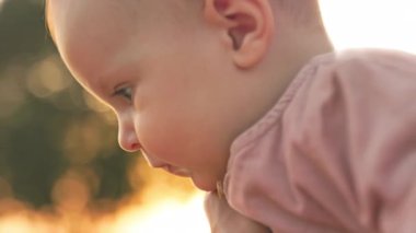 Kardeşine bakan, burunlarına dokunan beyaz bir kızın yakın plan fotoğrafı. Aile, arkadaşlar. Ergen ve yeni yürümeye başlayan çocuk. Açık havada. Gün batımının bulanık arkaplanı. İyi akşamlar. Doğa