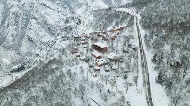 Kış mucizesi. Karlı kırsal arazide çarpıcı bir uçuş. Tepelerdeki güzel köy evleri. Manzaralı doğal ortam. Seyahat kavramı.