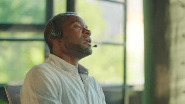 Kendine güvenen muhteşem iş adamının mikrofonlu kulaklıkla video görüşü. Uzaktan görüşmede el kol hareketi yapan güzel sakallı bir adamın portresi. Online iş. Motivasyon konsepti. Arka plan bulanık. Kapalı