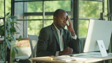 Orta yaşlı, yakışıklı, kendinden emin bir Afrikalı ofis çalışanının bilgisayar başında oturduğu görüntüler. Korkunç baş ağrısından muzdarip yorgun bir adamın portresi. Yorgunluk. Kapalı