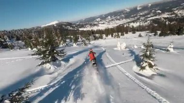 Dağlardaki güzel hava manzarası, kar motosikletli bir adam kışın güneş ışığında atlar ve ata biner. Güneşli bir günde