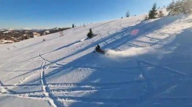 Dağlardaki güzel hava manzarası, kar motosikletli bir adam kışın güneş ışığında atlar ve ata biner..