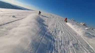Dağlardaki en iyi hava manzarası. Kar motosikletli iki adam kışın güneş ışığında atlayıp geziyorlar. Güzel manzara