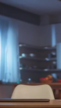 Mor gömlekli bir adam mutfaktaki dizüstü bilgisayarda çalışır, ev ofisine geçer, sonra da kendine güvenen bir şekilde karatahtaya sunar.