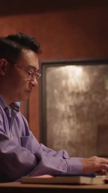 Videoda, gözlüklü, iş aşamalarında yol gösteren odaklanmış bir adam görülüyor. Masa başında yazar, belgeleri inceler ve loş bir odada çalışır.