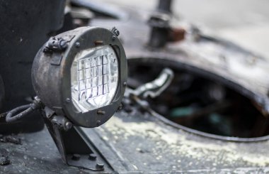 Sovyet savaş tankının ön farları. Tank taretinde çok parlak bir projektör, yakın plan. Zırhlı piyade savaş aracı. Eski bir zırhlı personel taşıyıcısının parçası, haki rengi far.