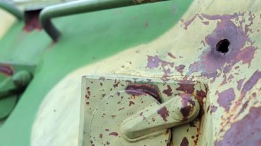 Ukrayna 'da savaş, bir piyade savaş aracının zırhında bir delik, zırh delinmiş. Yeşil kamuflaj zırhlı metal dokusu. Hasar ve delikleri var. Yok edilmiş askeri zırhlı personel taşıyıcısı.