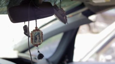 The icon amulet in the car of Nicholas the Wonderworker on a cord. The badge hangs conveniently on the rear-view mirror in the car. Translation: Seraphim of Sarov the Wonderworker
