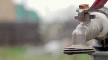 Doğanın arka planında su musluğu var. Su tasarrufu için musluğu açmak ya da kapatmak su sıkıntısı olduğunu gösterir. Gün ışığıyla taşra çeşmesi. Bulanık arkaplan ile seçmeli odak