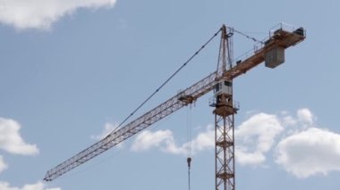 A working construction tower crane against a cloudy sky on a sunny day. The concept of urban development and construction. Industrial background. Crane engineering, construction industry tool
