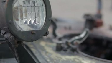 Sovyet savaş tankının ön farları. Tank taretinde çok parlak bir projektör, yakın plan. Zırhlı piyade savaş aracı. Eski bir zırhlı personel taşıyıcısının parçası, haki rengi far.
