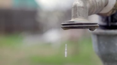 Doğanın arka planında su musluğu var. Su tasarrufu için musluğu açmak ya da kapatmak su sıkıntısı olduğunu gösterir. Gün ışığıyla taşra çeşmesi. Bulanık arkaplan ile seçmeli odak