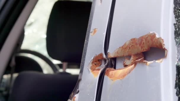 車のドアの弾丸の穴 弾丸の穴のある放棄された車 ウクライナの戦争地帯で破壊された車両 破損した民間車 戦闘の結果車は破片で損傷した — ストック動画