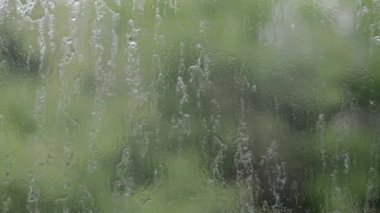 Heavy rain. Raindrops on the window glass on a summer day. Selective focus, shallow depth of field. Drops of water fall on a wet window. Glass full of drops during a downpour. Panorama